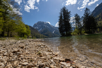 Gravel shore of an alpine lake on a sunny day.