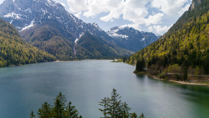 Aerial photo of a beautiful tranquil alpine lake beneath the mountains on a sunny day.