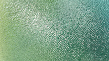 Aerial photo above the calm water of an alpine lake on a sunny day.