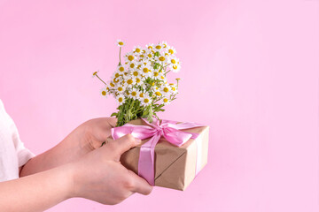Child's hands with flowers and gift for Mother's Day