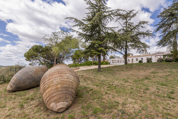 Two large clay jars on the plot of an Andalusian-style country house with white walls, gravel paths...