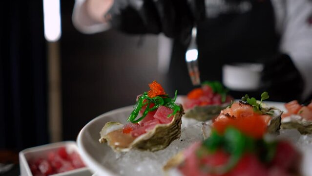 Red salmon fish with caviar and spices rests on an oyster shell. Seafood dish in an expensive luxury restaurant. Japanese unusual gourmet food