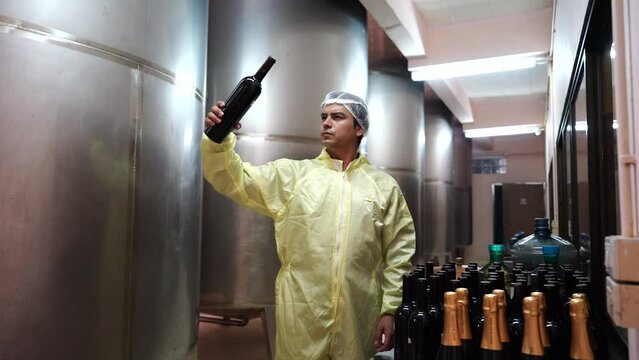 Winemaker man  wearing a sterile suit working and inspecting wine tanks in a large winery factory drink industry quality wine and fermentation monitor in a wine factory