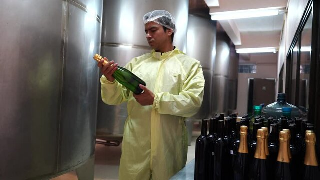 Winemaker man  wearing a sterile suit working and inspecting wine tanks in a large winery factory drink industry quality wine and fermentation monitor in a wine factory