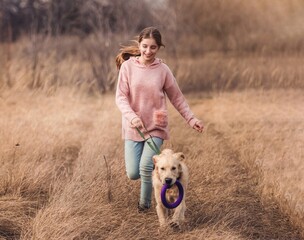 Playful dog running with teenage girl outside