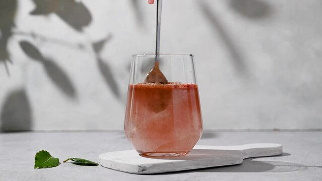 Protein collagen pink powder, fruits and vegetables powder, food supplement in a glass with water