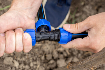 A man installs an automatic drip irrigation system for his garden. Fixing and connecting pipes...