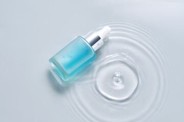 Bottles of cosmetics with a dropper in water on a blue background.