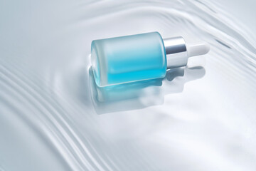 Bottles of cosmetics with a dropper in water on a blue background.