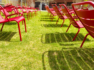 empty red chairs arrangement in a summer garden, outdoor events and meet ups, ceremony decor celebration on a sunny day