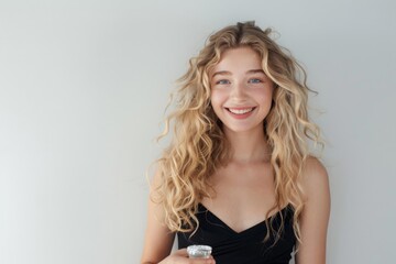 Fototapeta premium a beautiful blonde girl with long curly hair and a beautiful smile, standing in a confident pose. wearing a black cocktail dress,