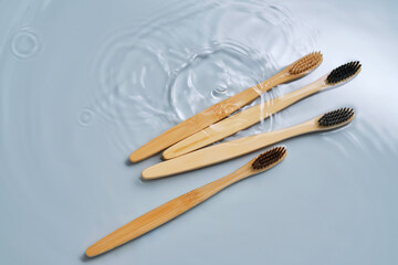 Natural bamboo toothbrushes in water on a blue background.