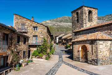 Village church with stone houses around next to the mountain, Castilla la Mancha, Spain.