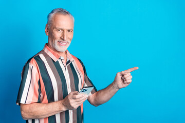 Photo of handsome nice senior man wear striped trendy clothes promoting empty space isolated on blue color background
