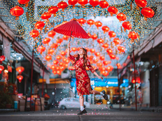 A woman wearing a Chinese New Year costume holds a red umbrella