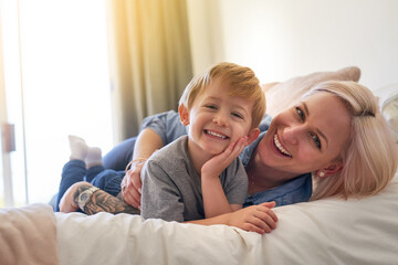 Mom, boy child and relax on bed in family home for love, happiness and care in apartment. Woman,...