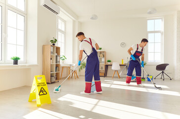 Efficient cleaning service in action. Two professional cleaners in uniform diligently clean floor...