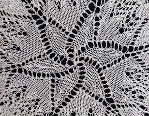 Vintage handmade white knitted napkin isolated on a black background.