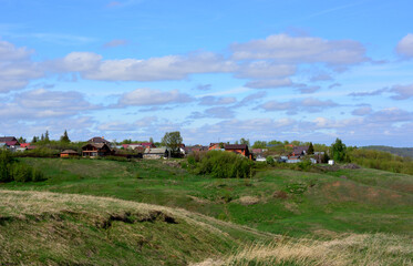 Obraz premium a hill with cottages and a sky with clouds in the background