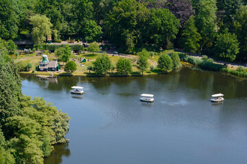 The blue river with three white boats near the forest. Three white boats are floating near the big public park