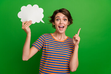 Portrait of smart overjoyed girl point finger hand hold empty space cloud shape bubble isolated on green color background