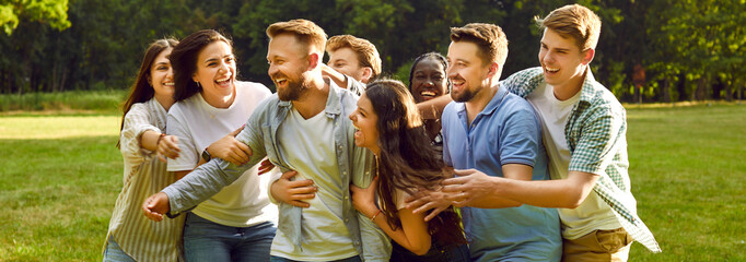 Joyful group of happy laughing people friends hugging in the summer park and smiling. Young...