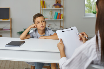 School counselor, psychologist or teacher having conversation with little child boy, holding...