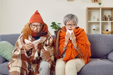 Flu like symptoms. Frozen elderly couple is sick at home during autumn cold and suffers from colds....