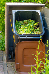 filled organic waste garbage can in the garden