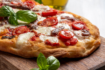 Deliziosa pinsa romana condita con mozzarella, pomodorini e acciughe, cibo italiano 