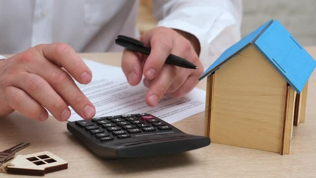 Man calculating mortgage cost on calculator close up. Expenses on refinancing of home loan. Real estate investment concept