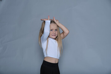 Creative child engaged in playful antics, her hands mimicking rabbit ears, capturing the essence of...