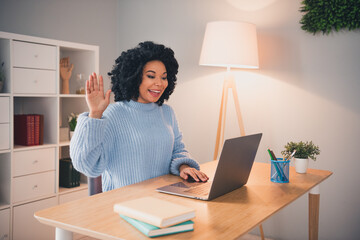 Portrait of pretty young lady wear sweater arm wave hi video call laptop desk home office indoors