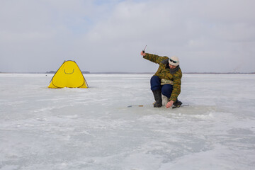 A man is engaged in winter fishing on a frozen lake.