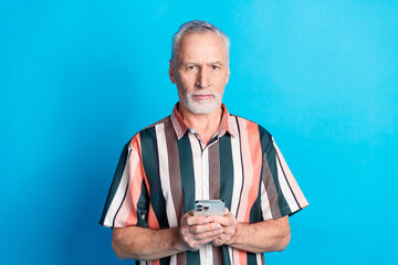 Photo of handsome nice senior man wear striped trendy clothes use modern device isolated on blue color background