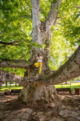 Beautiful woman with gorgeous curly hair doing yoga in nature, dressed in white and yellow combination, concept: active healthy life, in love with nature, support, balance, wellbeing, energy