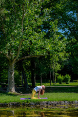 Beautiful woman with gorgeous curly hair doing yoga in nature, dressed in white and yellow combination, concept: active healthy life, in love with nature, support, balance, wellbeing, energy