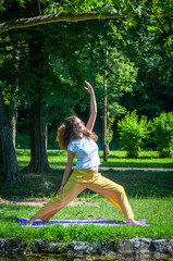 Beautiful woman with gorgeous curly hair doing yoga in nature, dressed in white and yellow combination, concept: active healthy life, in love with nature, support, balance, wellbeing, energy