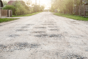 Gravel road with big potholes. Effects of weather and heavy use. Urban environment