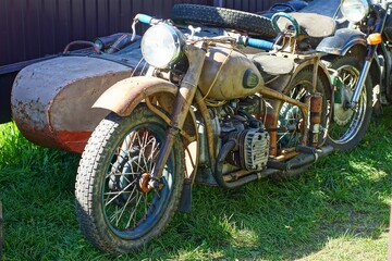 one retro beige  iron old rusty broken dirty motorcycle with a  sidecar  stands on the green grass...