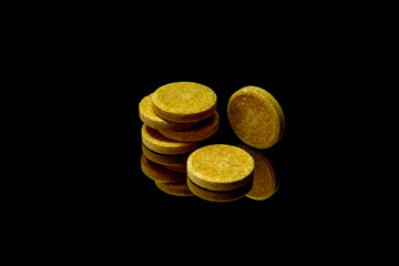 yellow vitamin pills on a black background with reflection.