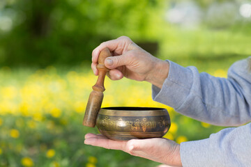 women's hands hold singing bowls in outdoor. Sound therapy, recreation, meditation.