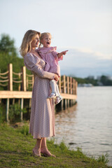 Mother and daughter laugh by the river, a shared moment of joy. Perfectly depicts family happiness...