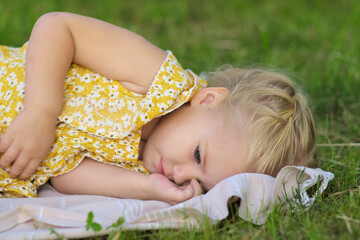 Little one in repose on green grass, summer vibes. A symbol of simplicity and the restful nature of childhood.