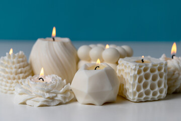 Soy wax handmade candles on white table against blue background. Delicate scented candle made of natural materials.