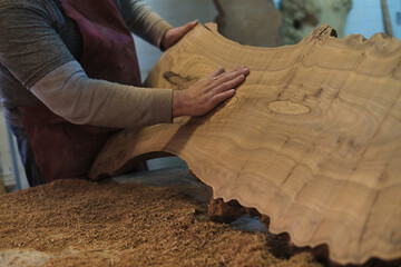 A craftsman admires the natural beauty of a large wood slab. The rich textures tell a story of the...