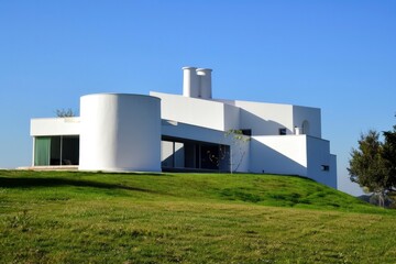 white colour modern structured house with empty grass field infront it and blue sky background