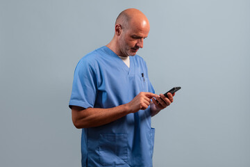 Portrait of a physiotherapist wearing a light blue coat and using a smart phone.