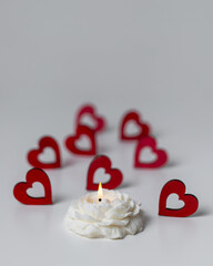 Handmade soy wax candle in flower shape and red hearts on white background. Valentine's day, romance, love concept. Copy space for text