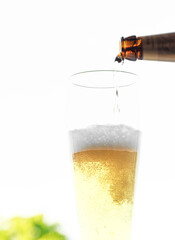 Bier wird aus einer Flasche in ein Glas eingeschenkt, sprudelnde Blasen und Schaum sind sichtbar